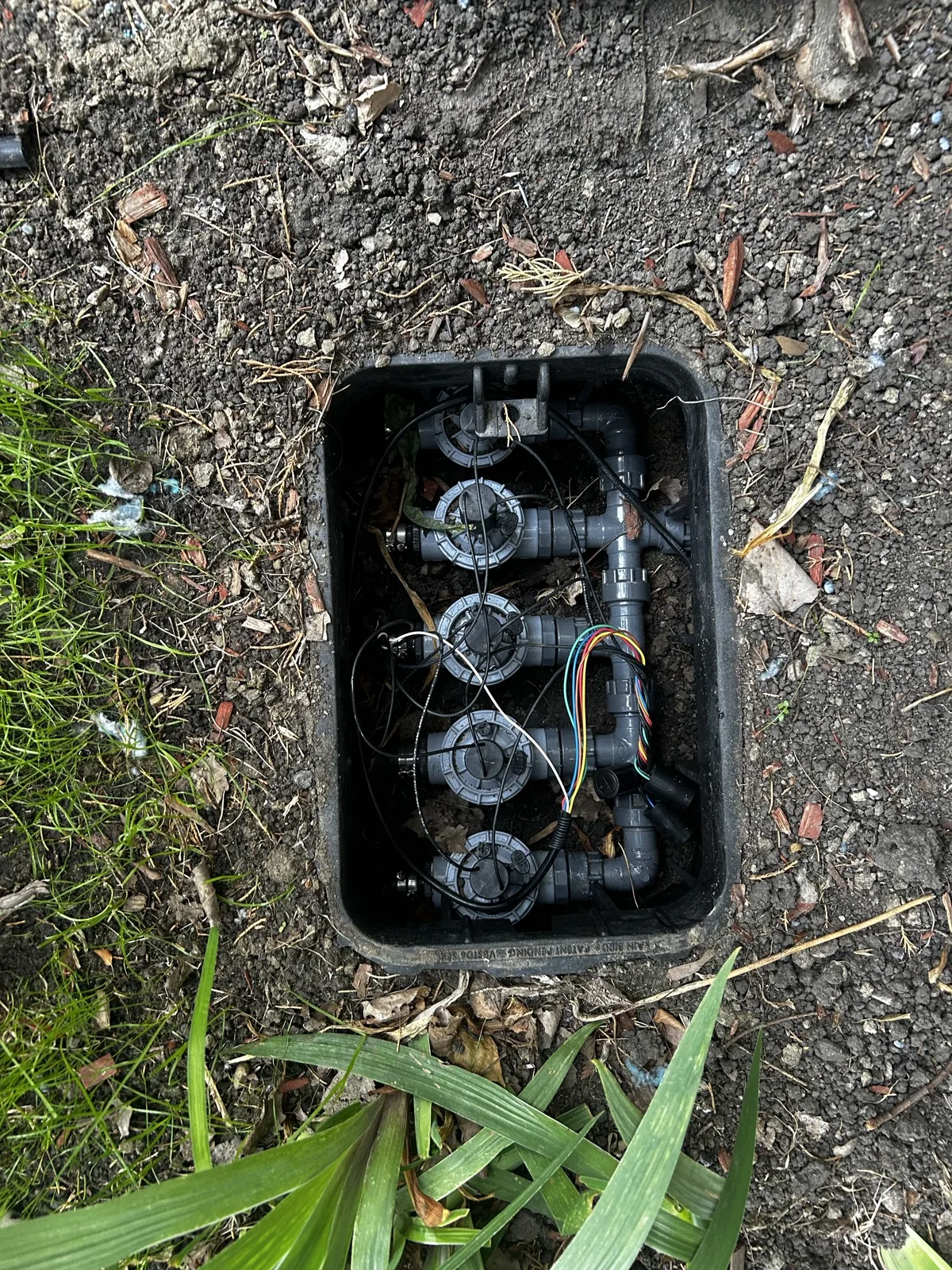 An in-ground irrigation valve box with solenoids and wiring during an AN Irrigation repair